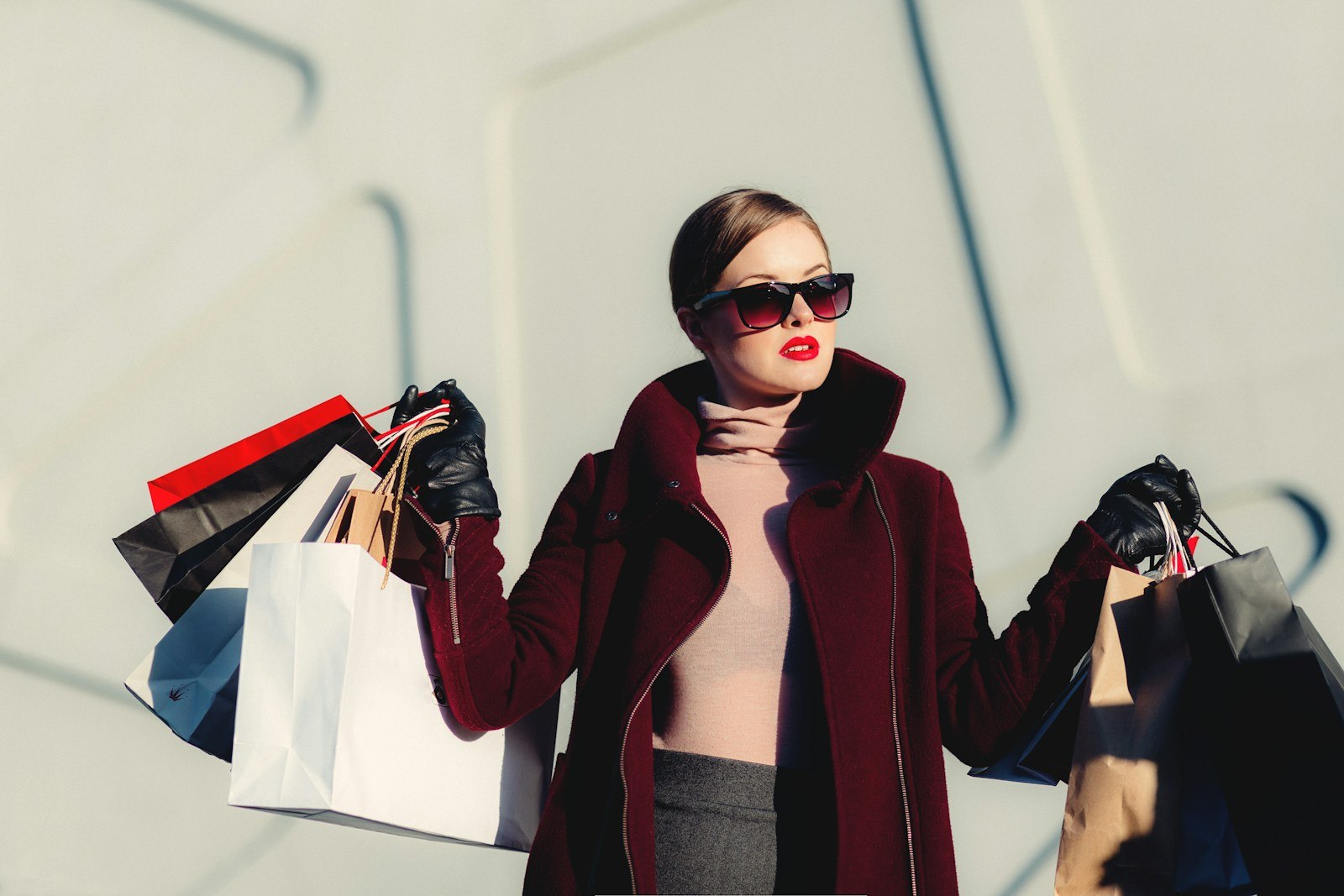 Woman styling a deep burgundy coat and sunglasses in the city